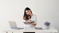 A businesswoman is taking notes while talking on the phone with someone at her desk Royalty Free Stock Photo