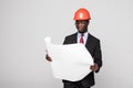 Professional black architect visiting construction site with blueprint plans and protective safety hard hat isolated on white