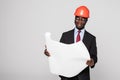 Professional black architect visiting construction site with blueprint plans and protective safety hard hat isolated on white