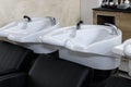 Professional black leather washing chairs with white wash sinks in hair salon interior Royalty Free Stock Photo