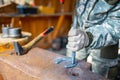 Professional blacksmith hand holding hammer, working with horseshoe at outdoor workshop - close up view. Handmade