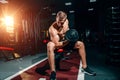 Professional bodybuilder, bodybuilder, sitting on a bench, doing exercises with dumbbells in the gym, training on the biceps. A Royalty Free Stock Photo