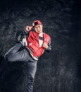 Professional breakdancer wearing fashionable clothes, warming up and stretching his legs for performance.