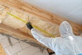 Professional builder man installing thermal insulation layer with fiberglass wool under the roof