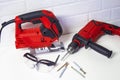 Professional building electrical tools for wood and metal. Electric jig saw and drill with safety glasses on a brick