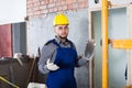 Professional builer in the helmet ready is plastering the wall