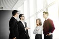 Professional business people standing around in informal group chatting as they wait for a meeting in office Royalty Free Stock Photo