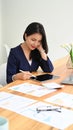 Professional business woman working with financial document and using digital tablet on wooden office desk Royalty Free Stock Photo