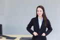 Professional business working Asian woman stands and put her hand in pocket of a black suit while she smiles happily in office as Royalty Free Stock Photo