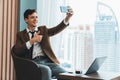 Professional businessman taking selfie near window with skyscraper. Ornamented. Royalty Free Stock Photo