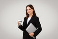 Professional businesswoman in a black blazer holding a laptop under her arm and a takeaway coffee cup Royalty Free Stock Photo