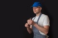 Professional butcher in black and white stripes apron, blue baseball hat, white shirt and glasses checking knive sharpness, black