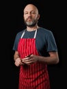 Professional butcher fishmonger wearing blue t shirt and classic red and white apron. Caucasian male in his 40s; black and grey