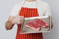 Professional butcher holding metal tray with two strip loin steaks. Premium high quality cut of beef. Meat industry. Thumbs up