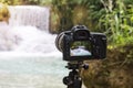 Professional camera photographing on a long exposure of a beautiful waterfall Kuang si in Laos. SLR camera on a tripod shooting a