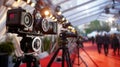 Professional cameras on tripods lining a red carpet event, capturing the glamor