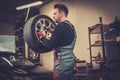 Professional car mechanic balancing car wheel on balancer in auto repair service.