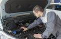 Professional car mechanic working in auto repair service with laptop