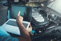 Professional car mechanic working in auto repair service using laptop Royalty Free Stock Photo