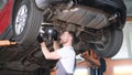 A professional car mechanic works under the king of a hoisting machine in a car repair shop. Royalty Free Stock Photo