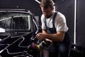 Car detailing and polishing concept. professional car service male worker use orbital polisher, polishing black car Royalty Free Stock Photo
