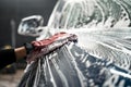 Professional car wash. Detailing worker washes the vehicle body with foam and rag.