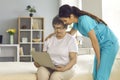 Woman nurse helping elderly lady patient with laptop at home lifestyle portrait Royalty Free Stock Photo