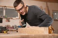 Professional carpenter grinding plank with jack plane in workshop