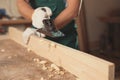 Professional carpenter grinding wooden plank with jack plane in workshop