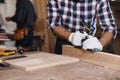 Professional carpenter grinding plank with jack plane in workshop, closeup