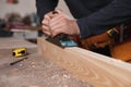 Professional carpenter grinding wooden plank with jack plane in workshop