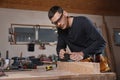 Professional carpenter grinding plank with jack plane in workshop