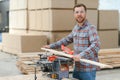 Professional carpenter using sawing machine for cutting wooden board at sawmill. Skilled cabinet maker working with Royalty Free Stock Photo