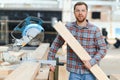 Professional carpenter using sawing machine for cutting wooden board at sawmill. Skilled cabinet maker working with Royalty Free Stock Photo