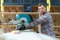 Professional carpenter using sawing machine for cutting wooden board at sawmill. Skilled cabinet maker working with Royalty Free Stock Photo