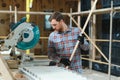 Professional carpenter using sawing machine for cutting wooden board at sawmill. Skilled cabinet maker working with Royalty Free Stock Photo