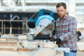 Professional carpenter using sawing machine for cutting wooden board at sawmill. Skilled cabinet maker working with Royalty Free Stock Photo