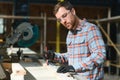 Professional carpenter using sawing machine for cutting wooden board at sawmill. Skilled cabinet maker working with Royalty Free Stock Photo