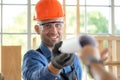 Professional carpenter wearing goggle and safety helmet receive blueprint or furniture diagram from customer. Worker smile and