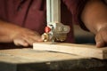 Professional carpenter working with sawing machine in workshop.