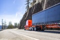 Professional carrier red big rig semi truck transporting cargo in tarp covered dry van semi trailer running on the mountain Royalty Free Stock Photo