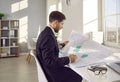 Professional cartographer working with printed cadastral map at table on his workplace.