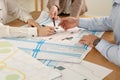 Professional cartographers working with cadastral map at table, closeup