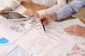 Professional cartographers working with cadastral map at table, closeup