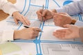 Professional cartographers working with cadastral map at table, closeup