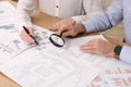 Professional cartographers working with cadastral map at table, closeup