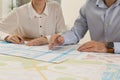 Professional cartographers working with cadastral map at table in office, closeup