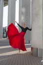 Professional Caucasian Ballet Dancer in Red Tutu Dress Posing in Red Skirt in Stretching Dance Pose With Lifted Hands and Against