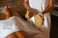 professional female physiotherapist masseuse performing brush massage to hispanic woman in spa clinic