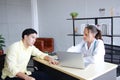 Professional Caucasian Female Psychiatrist MD is counseling and researching on website with laptop for treament asian man. Royalty Free Stock Photo